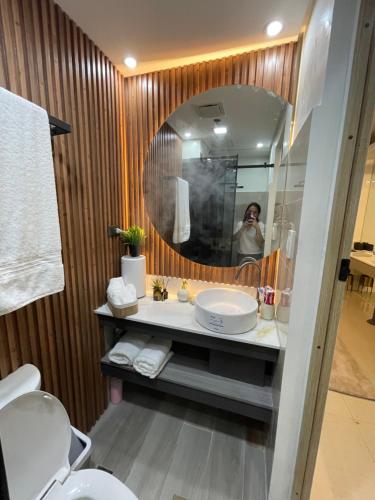 a woman taking a picture of a bathroom with a mirror at Yassi's Suite at MOA in Manila