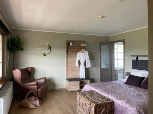 a bedroom with a bed and a chair and a mirror at Le Sommelet in Somme-Leuze