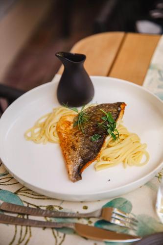 a plate of pasta with a piece of fish and sauce at Le Castel Cabourg hôtel & SPA- Restaurant La Calypso in Cabourg