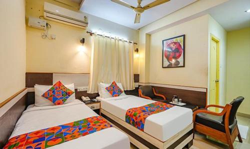 una habitación de hotel con 2 camas y una silla en FabHotel Sairam Residency, en Bangalore