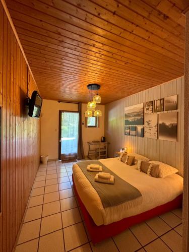 a bedroom with a large bed with a wooden ceiling at Logis Le Chalet in Saint-Maurice-en-Trièves