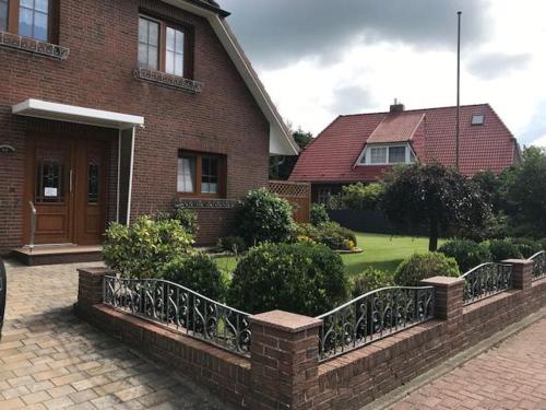 a brick house with a fence in front of a yard at Ferienwohnung Wellenkamp in Itzehoe