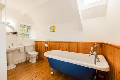 a bathroom with a tub and a toilet and a sink at Country House with Heated Swimming Pool & Gardens in Rhiw