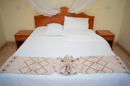 a bedroom with a white bed with a flower on it at Bekam Hotel in Keruguya
