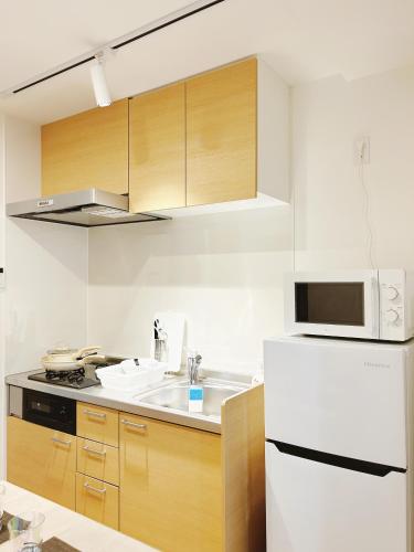a kitchen with a white refrigerator and a microwave at Tokyo Louis House in Ueno area close to JR Yamanote Line & Metro Ginza Line walk to Ueno Park and Ameyoko in Tokyo