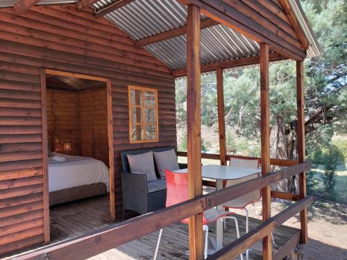 a wooden cabin with a bed and a table on a deck at Old Mill Drift Guest Farm in Clarens