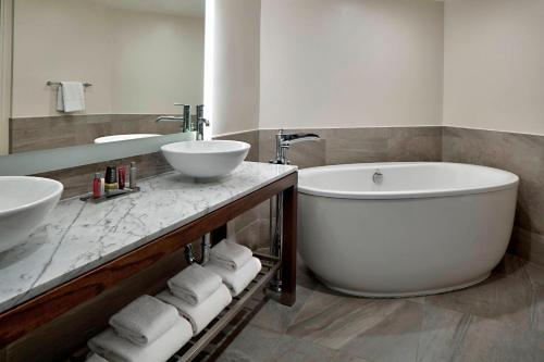 bagno con 2 lavandini, vasca e specchio di San Antonio Marriott Northwest Medical Center a San Antonio