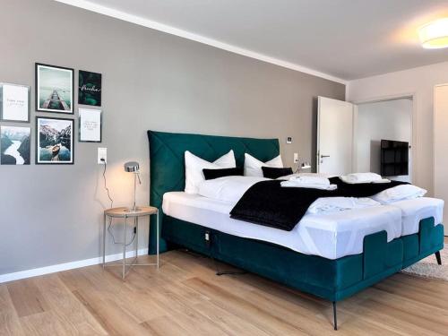 a bedroom with a large bed with a green headboard at Appartio: Geräumige, moderne Ferienwohnung für Gruppen/Familien in Stuttgart