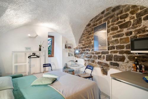 a bedroom with a bed and a stone wall at Grazioso open space in Sanremo