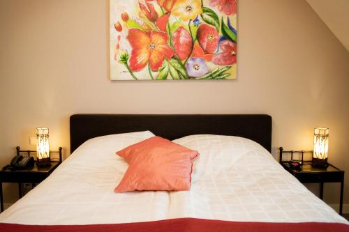 a bedroom with a bed with a painting on the wall at De Valkhoeve in Mill