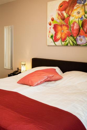 a bedroom with a bed with a painting on the wall at De Valkhoeve in Mill