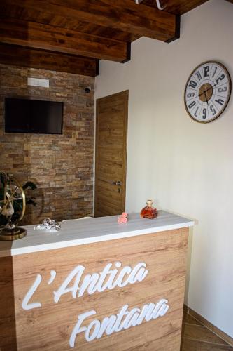 a clock on the wall above a counter with an antico foundation sign at L'Antica Fontana - Casa Vacanze B&B in Viggianello