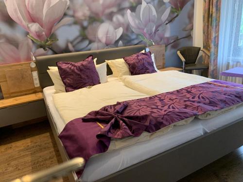 a bed with purple and white sheets and pillows at Hotel Paidion in Braunlage