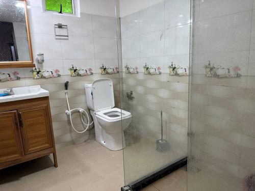 uma casa de banho com um WC e uma cabina de duche em vidro. em Villa in Kalviyankadu 