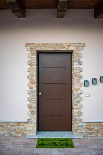 a brown door in a brick wall with a rug at L'Antica Fontana - Casa Vacanze B&B in Viggianello