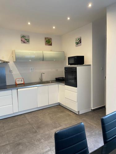 a kitchen with white cabinets and a black appliance at gites des cigognes in Dunkerque