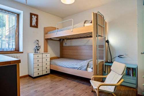 a bedroom with two bunk beds and a chair at Casa Magda in Tesero
