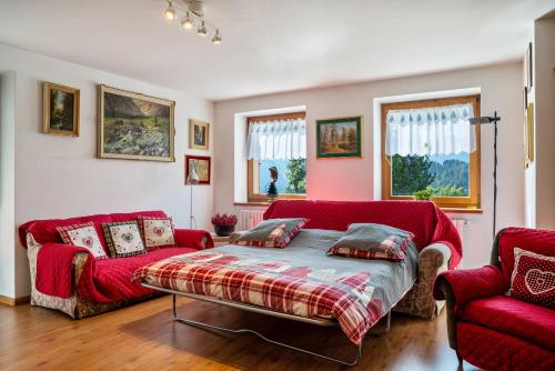 a living room with a red couch and two red chairs at Casa Magda in Tesero