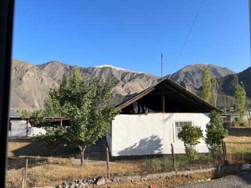 une petite maison blanche avec des montagnes en arrière-plan dans l'établissement Ata konush, à Sufi-Kurgan