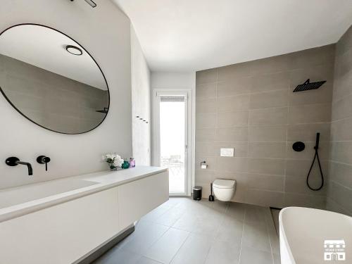 W łazience znajduje się biała wanna i lustro. w obiekcie ALTOPIANO by Design Studio w mieście Bellano