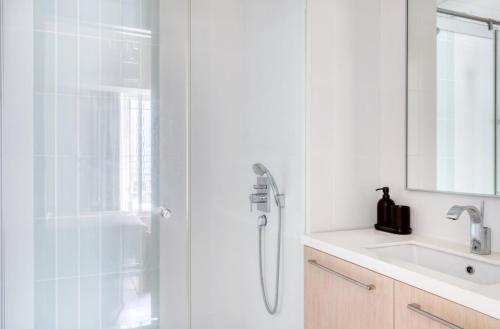 uma casa de banho branca com um chuveiro e um lavatório. em The Radiant Retreat 2BR apartment in Singapore em Singapura