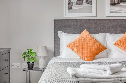 a bedroom with a bed with orange and white pillows at Contemporary 2 BR apt, town centre by tent serviced apartments in Chertsey