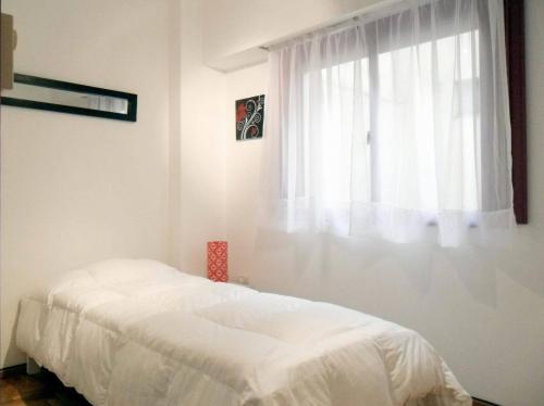 a white bedroom with a bed and a window at Apartment Dr.Romulo Naon in Buenos Aires