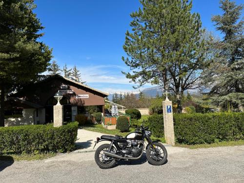a motorcycle parked in front of a house at Logis Le Chalet in Saint-Maurice-en-Trièves