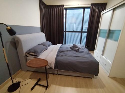 a bedroom with a bed with a table and a window at Icon Residenz Icon City, Petaling Jaya by De Harlequins Guesthouse in Petaling Jaya