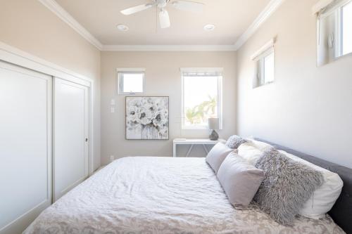 una camera da letto con letto, lenzuola e cuscini bianchi di 4048 Stylish condo in Hillcrest Mission Hills a San Diego