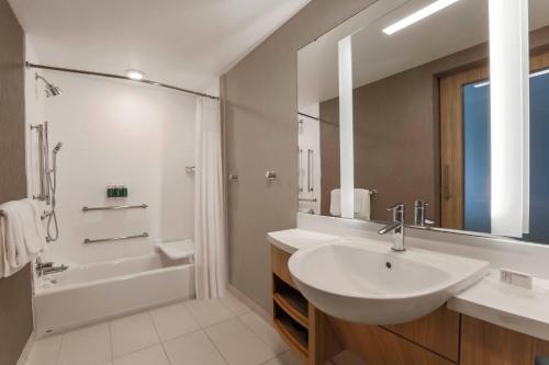 a white bathroom with a sink and a tub and a shower at SpringHill Suites by Marriott Tallahassee North in Tallahassee