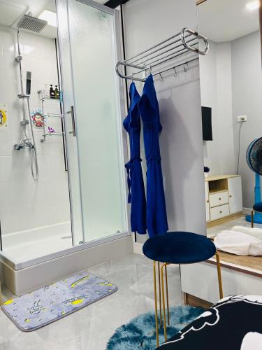 La salle de bains est pourvue d'une douche et d'un tabouret bleu. dans l'établissement KITJA MY HOME, à Hat Yai