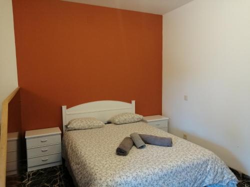 a bedroom with a bed with an orange wall at Apartamentos Buendia in Buendía
