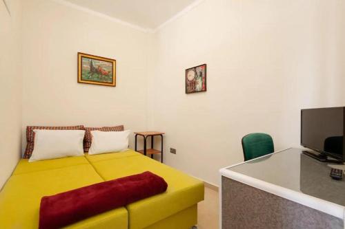 a bedroom with a yellow bed and a desk with a television at Thessaloniki_City_Center in Thessaloniki