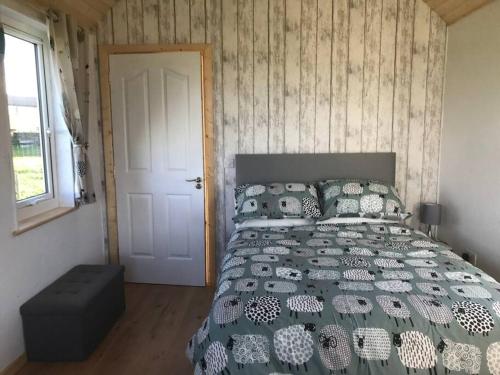 1 dormitorio con cama, ventana y puerta en The Snuggly Sheep Farm Stay Shepherd Hut, en Ballyshannon