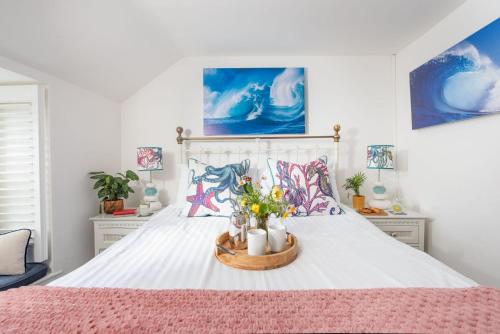 a bedroom with a white bed with flowers in a basket at Mariners Cottage, St Ives in St Ives