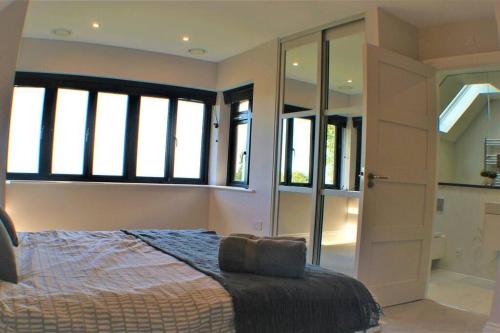 a bedroom with a bed and windows and a door at Stylish Seaview House with Hot Tub in Hythe