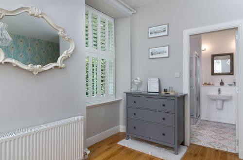 La salle de bains est pourvue d'un lavabo, d'un miroir et d'une commode. dans l'établissement Westwood Cottage, à Dundee
