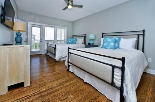 two beds in a bedroom with blue walls and wood floors at Sea Prize at Grayton Beach in Santa Rosa Beach