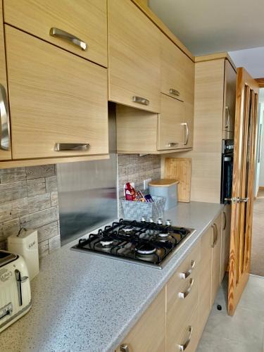 a kitchen with wooden cabinets and a stove top oven at New Holliday Villa, Anstruther in Cellardyke