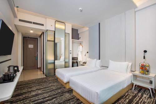 a hotel room with two beds and a television at THE 1O1 Jakarta Airport CBC in Tangerang