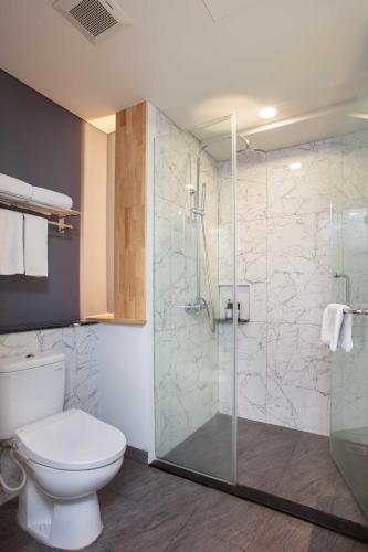 a bathroom with a toilet and a glass shower at THE 1O1 Jakarta Airport CBC in Tangerang