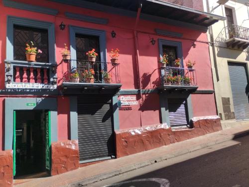 un edificio rosso con fioriere alle finestre di Hostal Flores a Quito