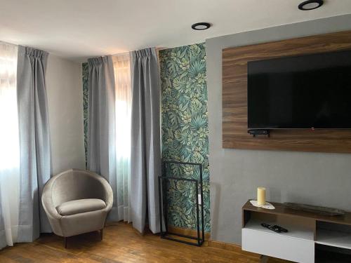 PASEO REAL HOTEL BOUTIQUE في اروابان دل بروغرسو: غرفة معيشة مع كرسي وتلفزيون بشاشة مسطحة