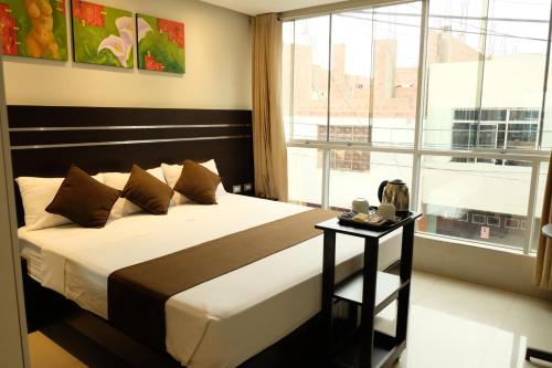 Hotel Puma'r Tacna في تاكنا: غرفة نوم بسرير ونافذة كبيرة