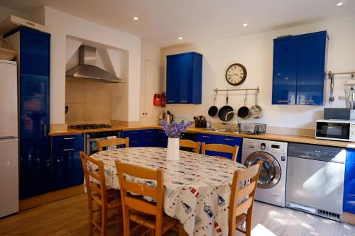 a kitchen with blue cabinets and a table with chairs at 2 Elgin House in Seaview