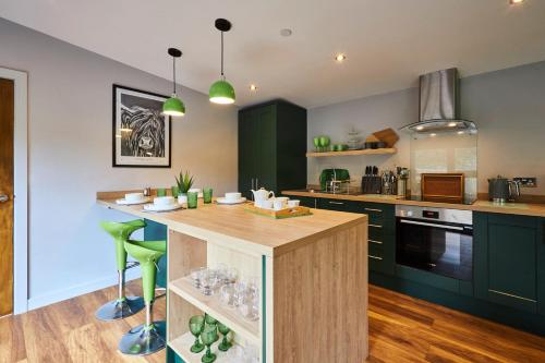 cocina con armarios verdes y encimera de madera en Host & Stay - Forest Green Lodge, en Alnwick