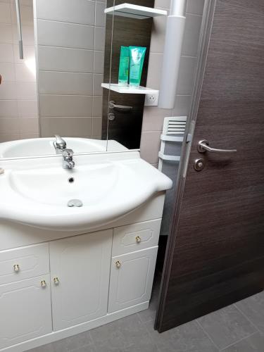 La salle de bains est pourvue d'un lavabo blanc et d'un miroir. dans l'établissement La Bienvenue, à Saint-Michel-sur-Meurthe