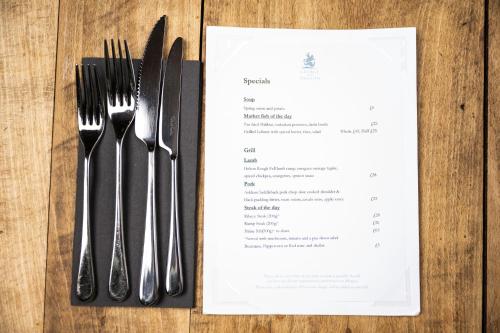 a table with forks and knives next to a menu at George and Dragon Clifton in Penrith