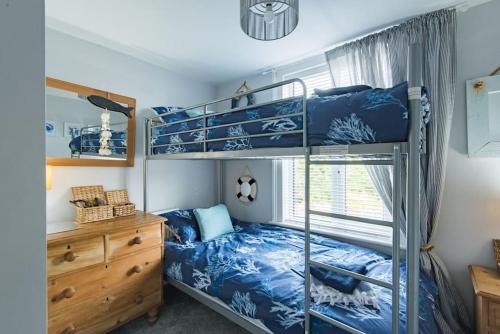 a bedroom with two bunk beds and a dresser at Driftwood - Charming family home in Deal